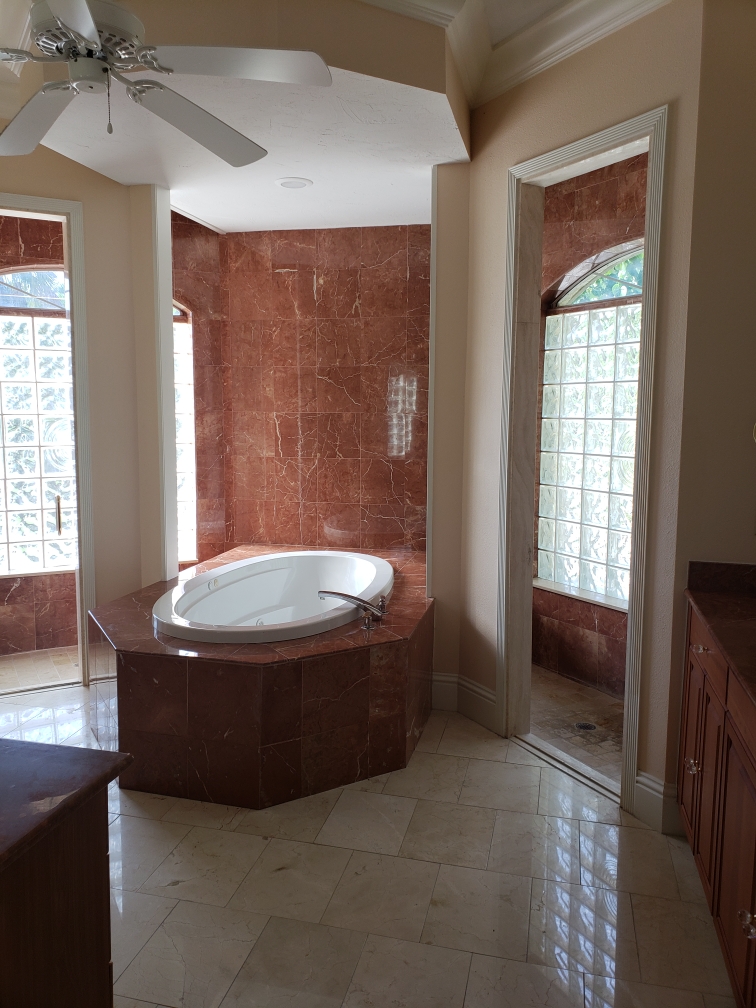 Primary bathroom before renovation with built-in tub and red stone